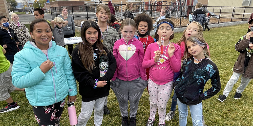 Students at the finish line eat an otter pop and wear their gold medals