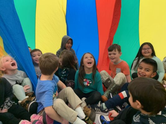 Students play inside the parachute in the gym for PE