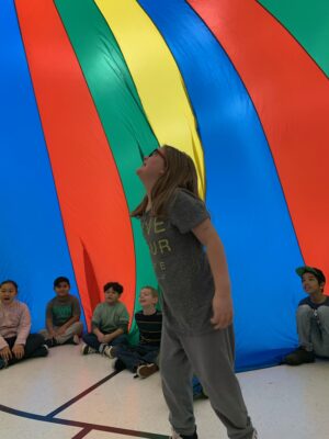 Students play inside the parachute in the gym for PE