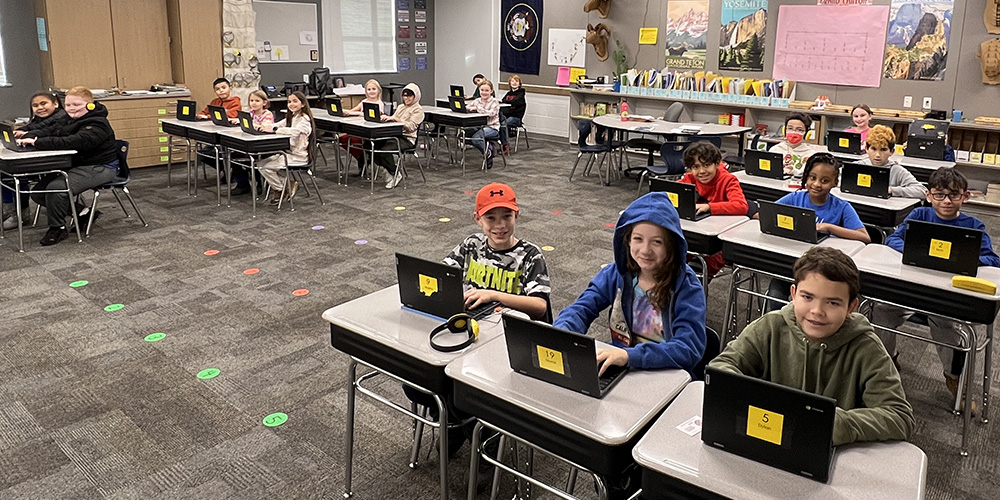 Students are at their desks with their Chromebooks.