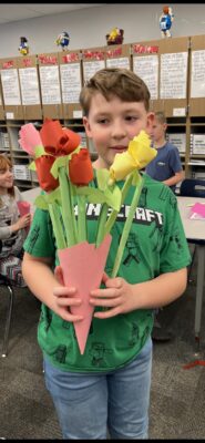 Student holding flowers from art class