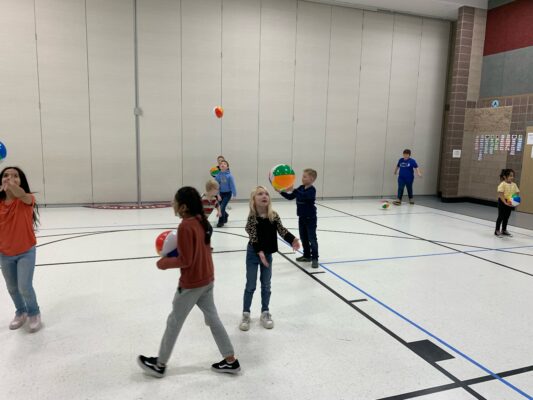 Students practice volleyball skills in the gym.