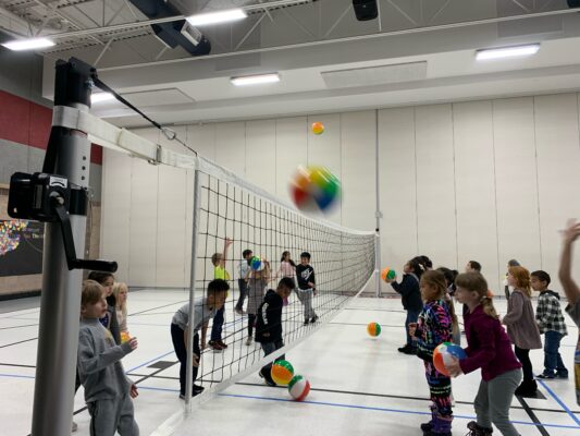 Students practice volleyball skills in the gym.